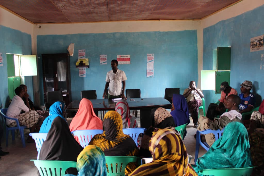 Et klasserom i Somalia med voksne kvinner og menn til stede sitter og snakker sammen.