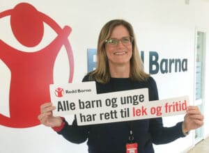 Birgitte Lange, generalsekretær i Redd Barna, holder en plakat hvor det står Alle barn og unge har rett til lek og fritid