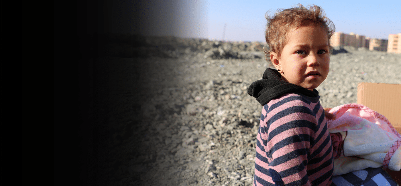 En ung jente mottar teppe og klær fra en nødhjelpspakke i Syria.