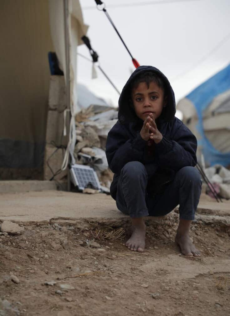 Firas*, 6, in front of their tent a displacement camp in Syria