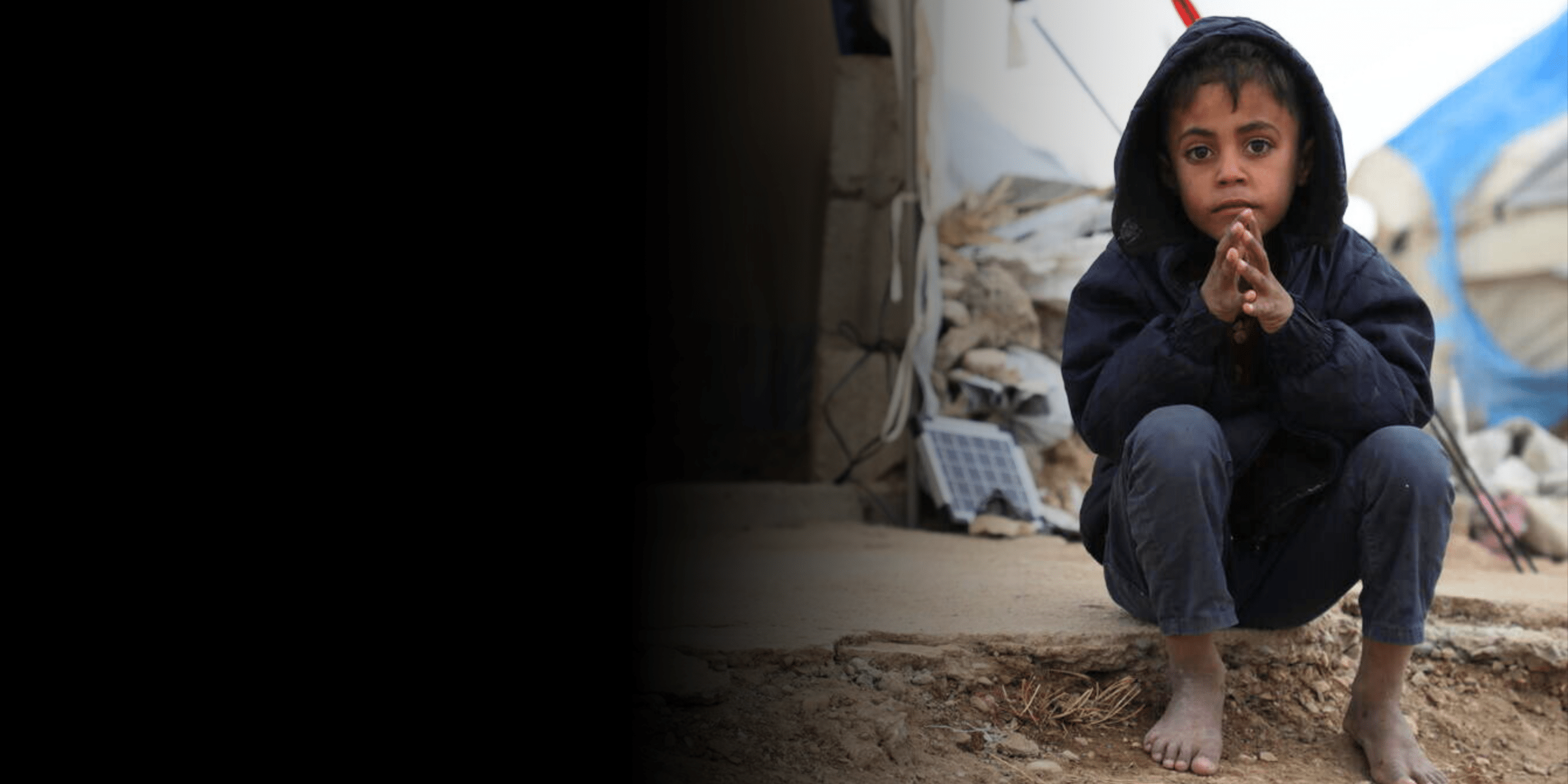 Firas*, 6, in front of their tent in a displacement camp in Syria