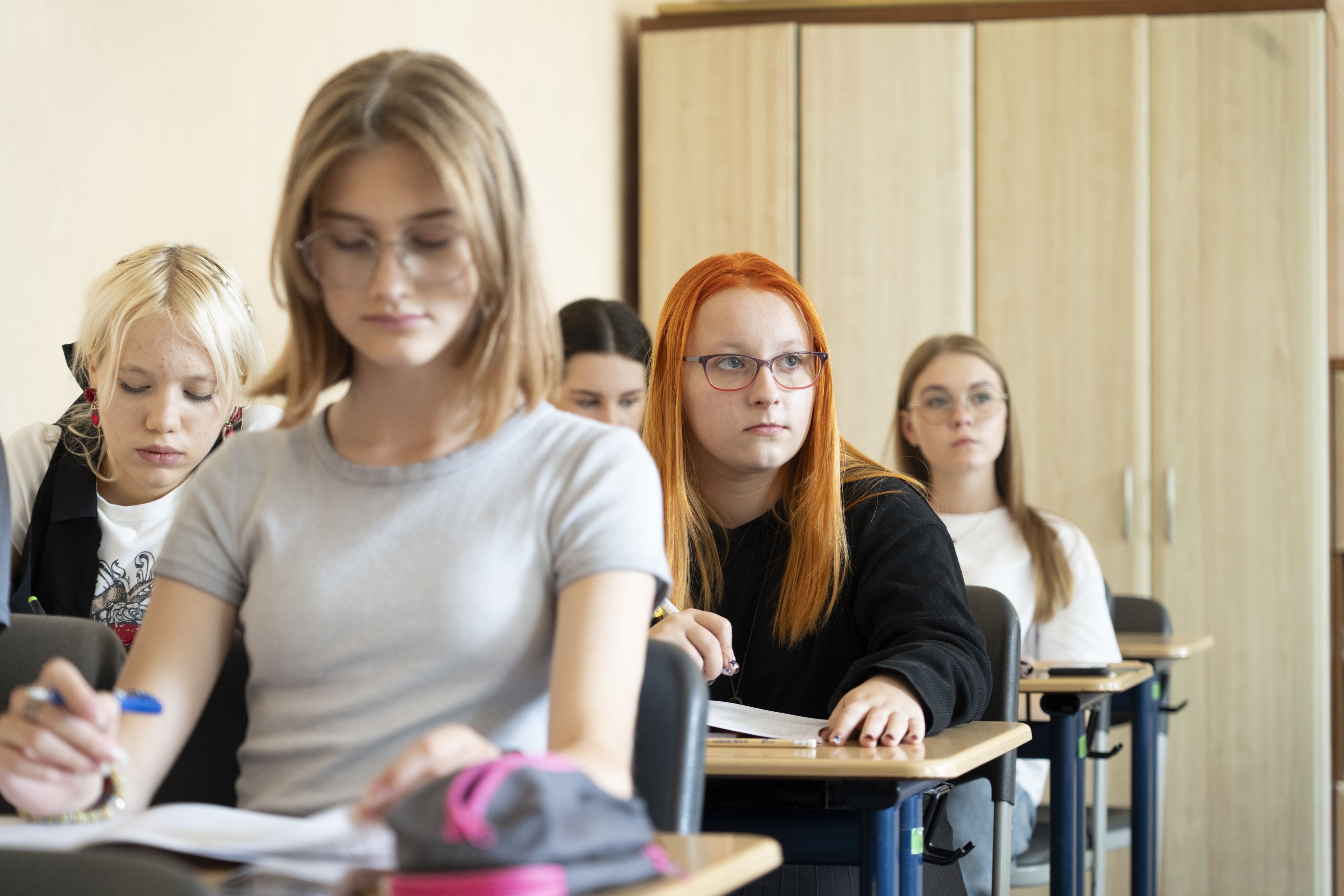 Kseniia sitter i klasserommet og ser ut i rommet.