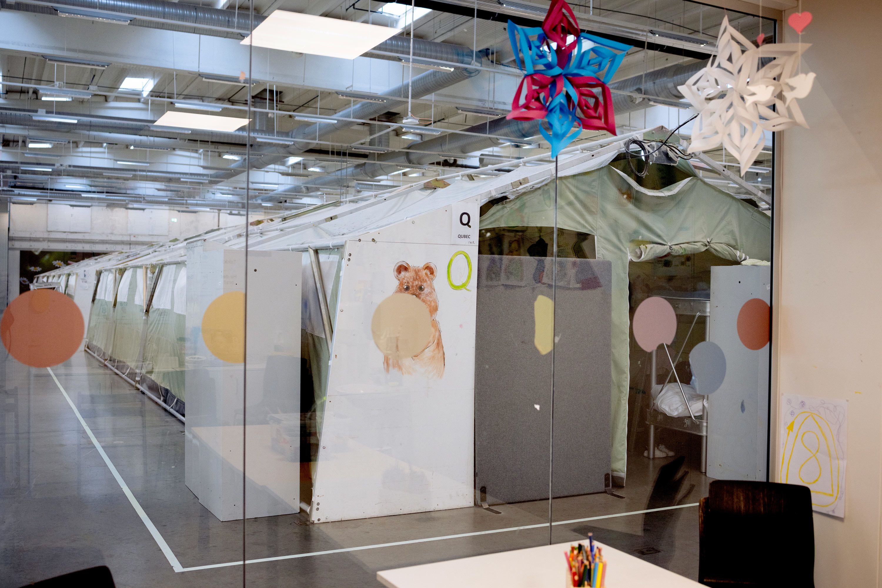 En rekke med telt i en stor hall. På det fremste teltet er det tegnet en kosebamse.