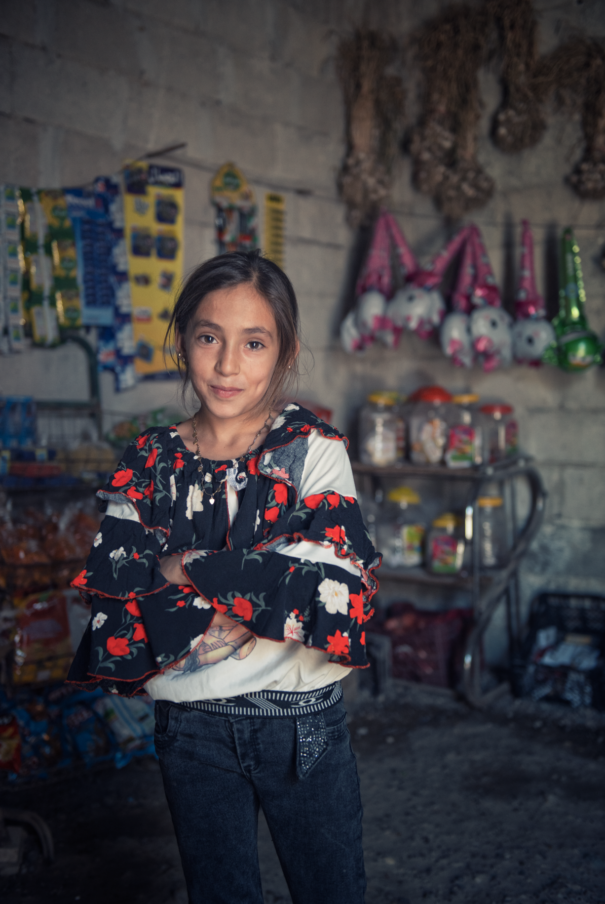 Aisha (11) står med hendene i kryss inne i butikken og smiler lurt til kamera.