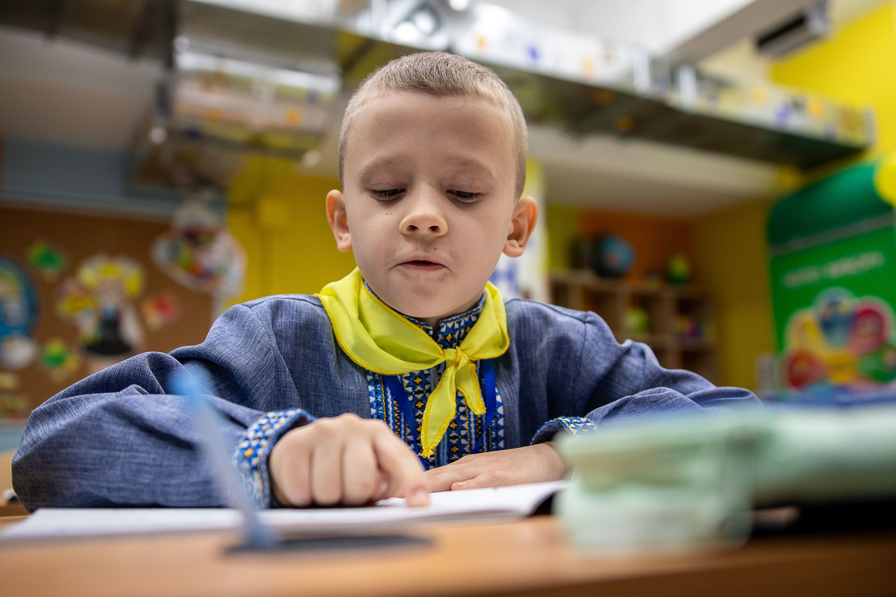 Artem sitter ved pulten og leser i skoleboken.