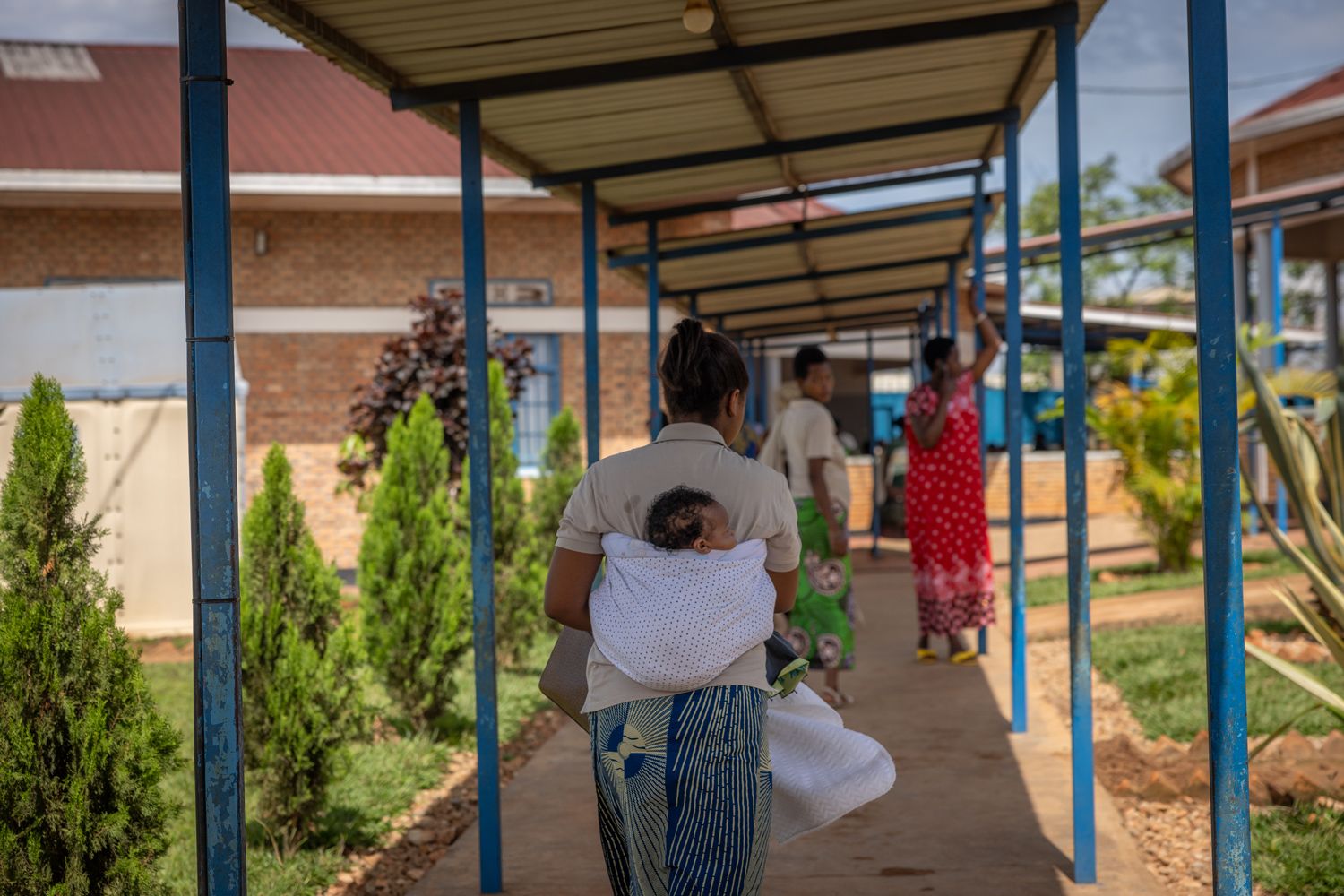 En kvinne, med en baby på ryggen, går bortover veien mot det medisinske senteret i Mahama leiren.