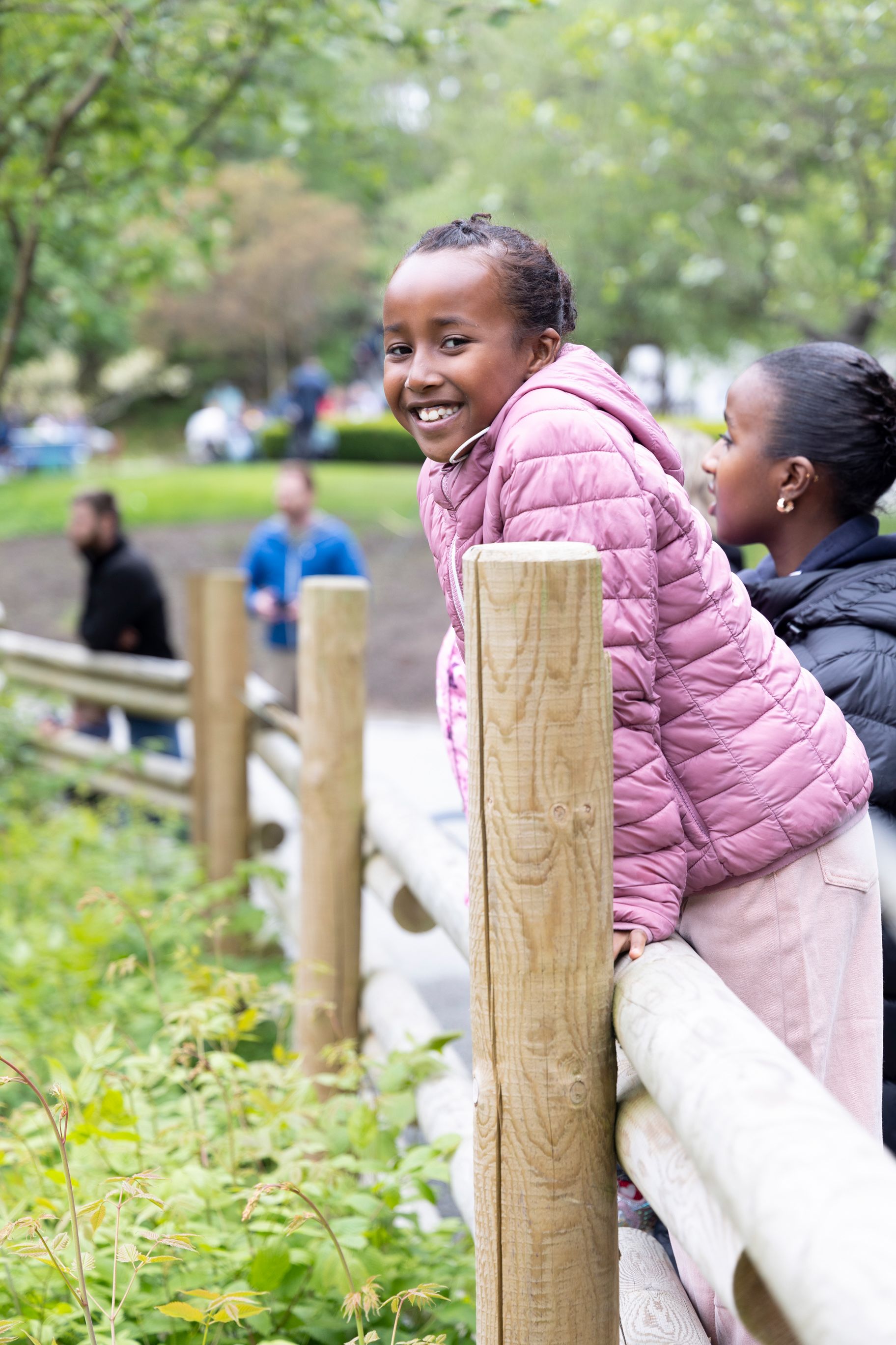 Sara står og lener seg på gjerdet i Kristiansand Dyrepark og smiler til kamera.